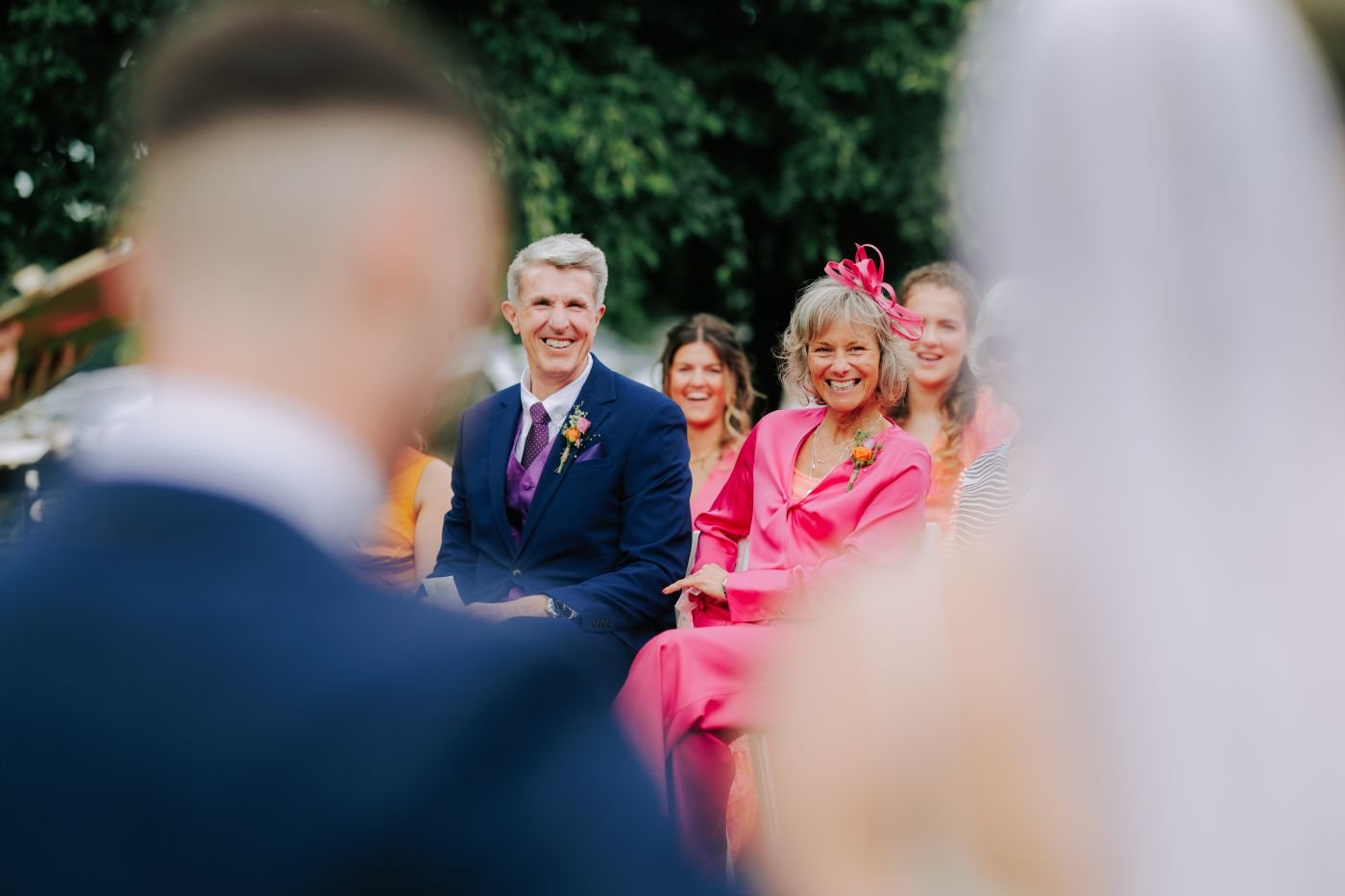 Wedding guests seated outdoors, laughing during the ceremony
